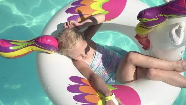 Happy child girl swims on an inflatable ring in an outdoor pool