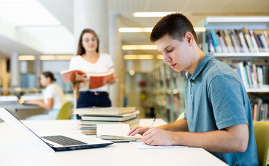 School student doing research on project in the college library