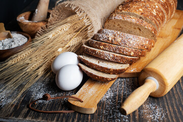 Fototapeta na wymiar loaf of rye bread, ears of wheat, eggs and a bowl of flour. Close-up.