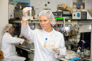 Female pharmacist researcher waiting for color change in test tube while conducting experiment in laboratory