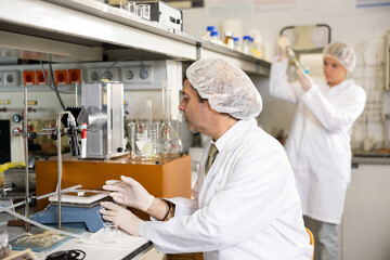 Adult male scientist chemist concentratedly weighs the capsules on the scales in the laboratory