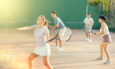 Sportive woman in shorts and t-shirt playing frontenis on outdoors court