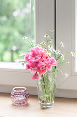 A small bouquet of poza geranium flowers, field daisies and spikelets in a glass