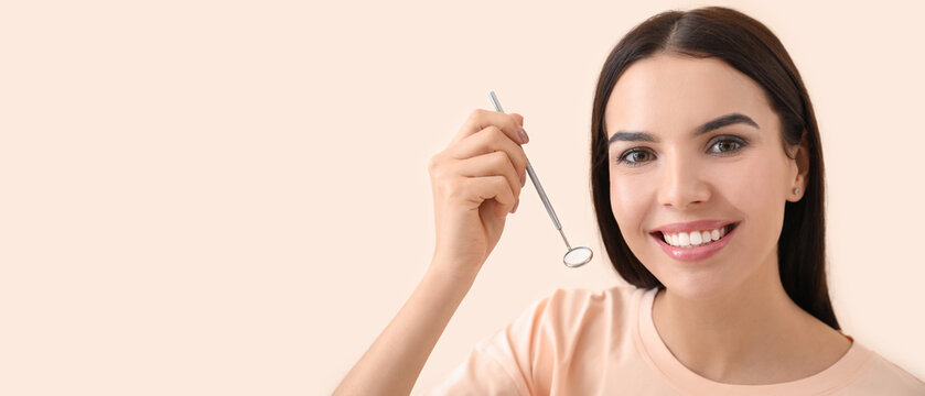 Beautiful young woman with dentist's mirror on light background with space for text