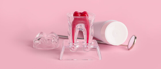 Obraz na płótnie Canvas Plastic tooth with paste and dental mirror on pink background
