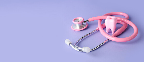 Plastic tooth and stethoscope on lilac background with space for text