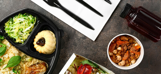Containers with delicious food for delivery on dark background