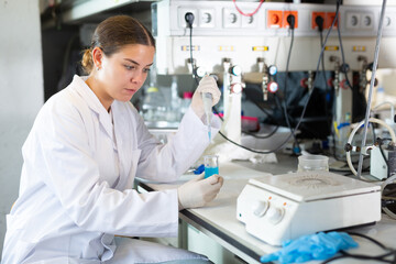 Concentrated woman scientist chemist works with liquids in beaker in science laboratory