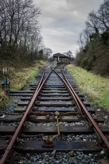 Fototapeta na wymiar Old railway station in the Irish countryside. Bifurcation in the railway tracks, rusty and rotten wooden sleepers.. Northern Ireland, UK