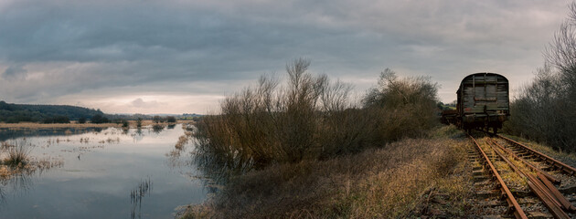 Panoramic landscape of sunset on the lake. Old train on the railway beside the marshes. Northern Ireland UK