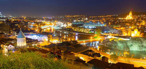 Fototapeta na wymiar Picturesque night view of Tbilisi with bridges over Kura river, capital of Georgia