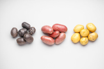 Heaps of different raw potatoes on light background