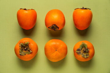 Fresh ripe persimmons on green background