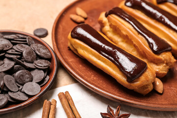 Plate with tasty eclairs and chocolate drops on color background, closeup