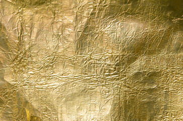 Gold foil texture background. Metallic crumpled foil paper texture close up. 