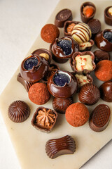 Board with chocolate candies on white background