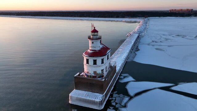 Dynamic drone video of lighthouse at dawn on lake in winter