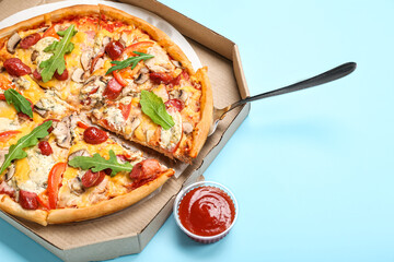 Cardboard box with tasty pizza and sauce on color background