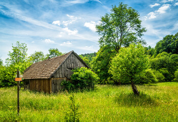 Stara drewniana chata na zielonej łące pod błękitnym niebem (Beskid Niski)