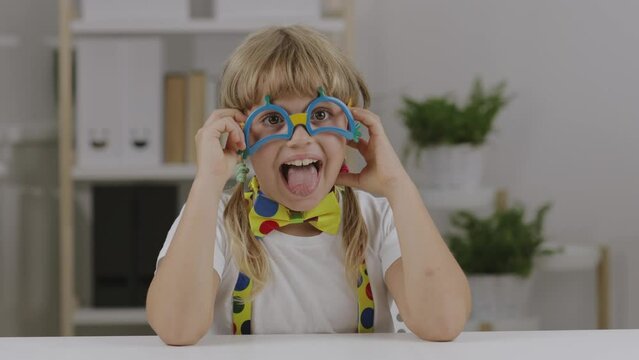 Funny girl of 7 years dressed in clown eye glasses, butterfly and suspenders.