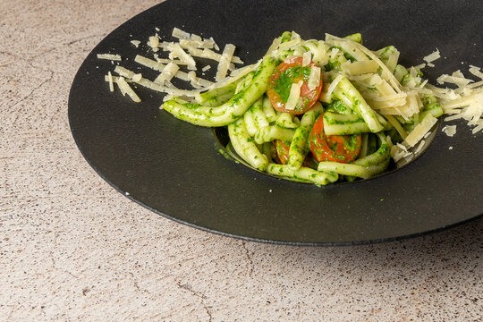 Troffi al pesto served with parmesan cheese served on an elegant black plate on a stone table. High quality photo