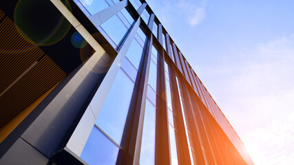 Glass modern building with blue sky background. Low angle view and architecture details. Urban abstract - windows of glass office building in  sunlight day. - obrazy, fototapety, plakaty