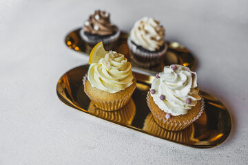 Closeup shot of artistic cupcakes with buttercream frosting and decorations served on golden plates. Copy space. High quality photo