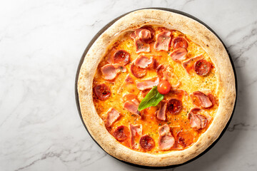 View from above of delicious salami, ham and cheese pizza on white marble table . High quality photo
