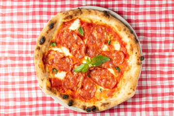 View from above of delicious salami, ham and cheese pizza on a checkered tablecloth. High quality photo