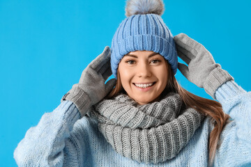 Young woman in winter clothes on blue background, closeup