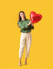 Young woman with balloon for Valentine's Day on yellow background