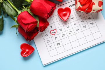 Calendar with marked date of Valentine's Day, gift, roses and candles on blue background