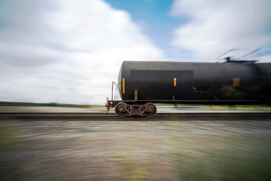 Storage tanks moving on railroad track against cloudy sky