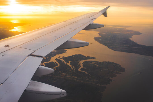 Cropped image of airplane flying over seascape against cloudy sky during sunset