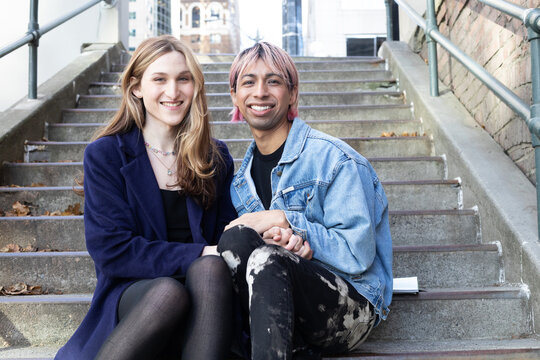 Lgbtqia friends posing on stairs outside.
