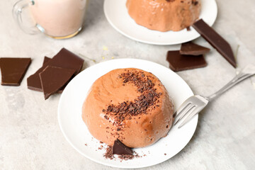 Plates with delicious pudding, chocolate and cup of milk on grey table