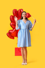 Beautiful woman with balloons on yellow background. Valentine's Day celebration