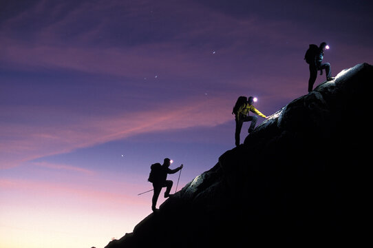Three people hiking in the mountains at night.