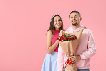 Happy couple in love with roses on pink background. Valentine's Day celebration
