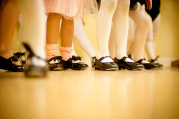 Low angle view of the tap shoe clad feet of a group of little girls, in a dance studio.