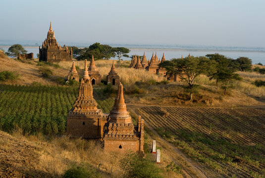 A group of 13th-century pagodas of varying sizes stand among farm fields lining the shores of the Irrawaddy river at Bagan, Union of Myanmar (Burma)