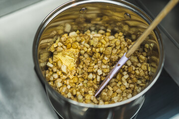 Cubed apple and butter seasoned with cinnamon in metal pot. Spatula being put in the pot. High quality photo