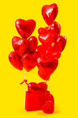 Shopping bag with heart-shaped balloons for Valentine's Day on yellow background