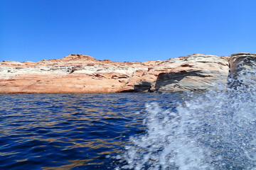 Fototapeta na wymiar Water splashing from a watercraft and Colorful sandstone rock formations along the Colorado River at Glen Canyon National Recreation Area 