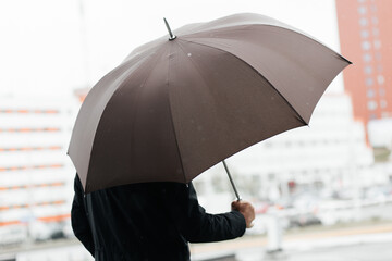 a man in business clothes holds a large umbrella in his hands