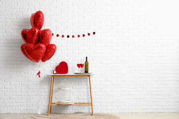 Engagement ring, wine and gift for Valentine's Day on table near white brick wall in room