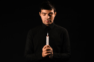 Praying Jewish man with candle on dark background. International Holocaust Remembrance Day