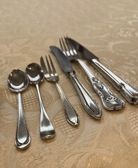 Row of elegant silver cutlery on a tablecloth.