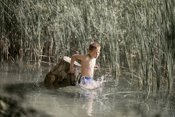 Lonely boy admiring the beauty of the summer lake in greece . Boy playing outside - imitate fishing at a lake.
