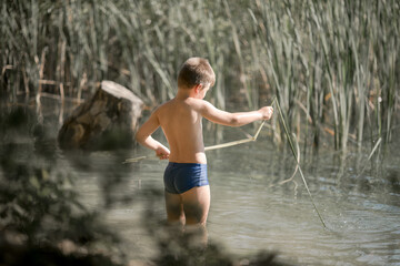 Lonely boy admiring the beauty of the summer lake in greece . Boy playing outside - imitate fishing at a lake.